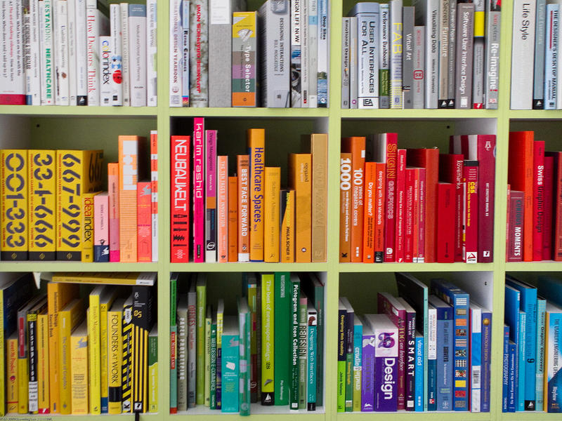 a bookshelf of books organized by color