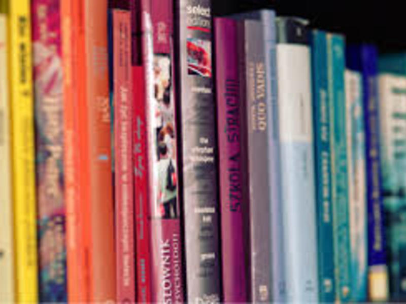 a close up of books on a shelf, organized by color 